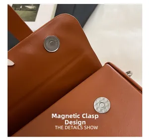Detailed macro view of the brown leather handbag magnetic snap closure with engraved hardware