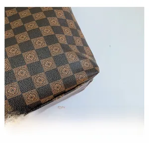 Close-up of brown checkered leather texture with symmetrical floral logo patterns