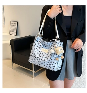 Dettaglio della borsa tote trapuntata azzurra con fiocchi neri e ciondolo di peluche