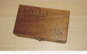 Detailed close-up of a 70-piece wooden alphabet and number stamp set in a solid storage box