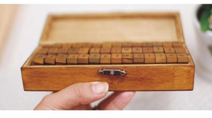 Detailed view of vintage wood stamp set with letters and numbers in a rustic storage box