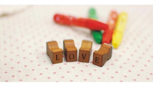 Detailed view of four wooden alphabet stamps spelling LOVE on a pink polka dot background
