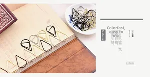 Detail of drop-shaped metal paperclips in gold and silver on a vintage notebook