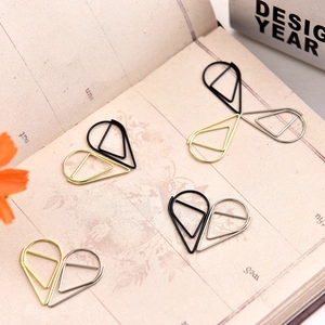 Creative heart-shaped paper clips in gold, silver, and black on a vintage notebook