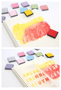 Détail de tampons encreurs colorés appliqués sur un carnet à l'aide de pochoirs lettres