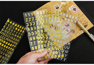 Close-up of metallic gold and silver 3D alphabet stickers for DIY scrapbooking