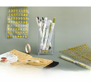 Close-up of golden letter and number stickers decorating a stationery holder and notebook