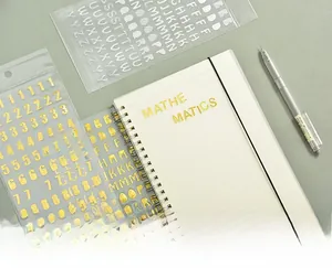 Close-up of gold and silver metallic alphabet stickers applied on a DIY notebook cover