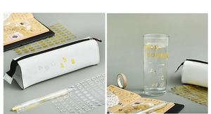 Detailed application of gold metallic letter stickers on pencil case and notebook