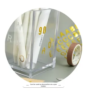 Close-up of gold and silver metallic letter stickers on a transparent pen holder
