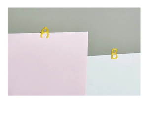 Close-up of golden metal A and B letter-shaped bookmarks on textured cardstock