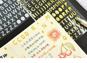 Detail view of gold and silver metallic alphabet stickers applied on a dark notebook