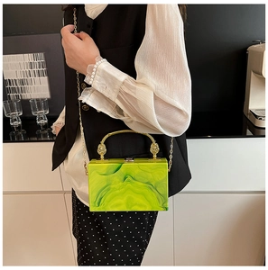 Detail of green marble acrylic clutch with gold metal handle and long chain strap