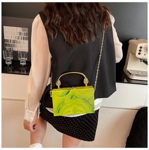 Detail of green marble acrylic clutch with elegant golden handle and metal chain strap
