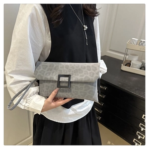 Detail shot of grey leopard print clutch bag with black square buckle and wrist strap