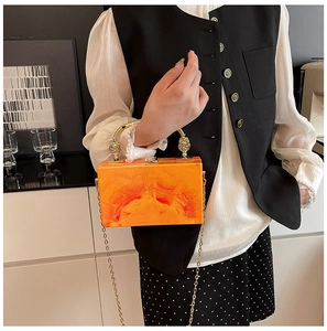 Detail of orange marble acrylic evening clutch with gold metal handle and chain strap