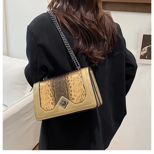 Detail of snake print leather flap with diamond rotary lock on chain crossbody bag