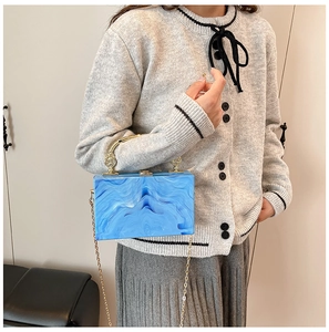 Blue marble acrylic clutch bag with gold handle and chain shown on model