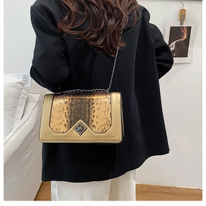 Detail of snake print flap and gold metal twist-lock on a stylish crossbody bag