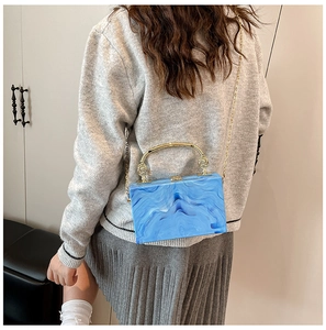 Detail of blue marble acrylic clutch bag with gold handle and metal chain strap