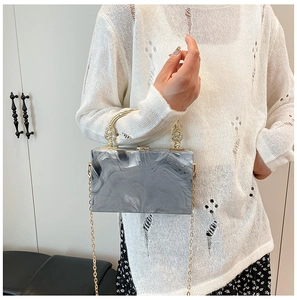 Detail van marmeren acryl box clutch met vintage gouden handvat en fijne kettingriem