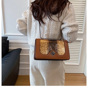 Detail of snake skin pattern on brown leather bag paired with cream knit sweater