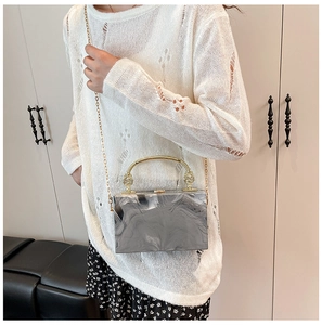 Detail van de marmeren acryl box clutch met gouden metalen handvat en ketting op model