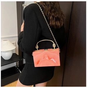 Detail van de oranje marmeren acryl box tas met goudkleurig handvat en kettingriem op een model