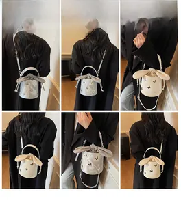 Detail view of silver and cream bucket bags with bow embroidery and rabbit ear drawstring