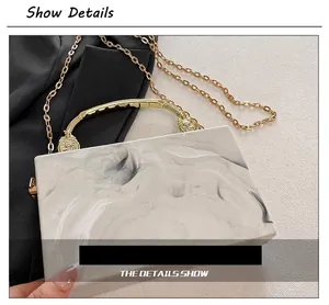 Detail view of acrylic marble evening clutch featuring gold lion head handles and chain