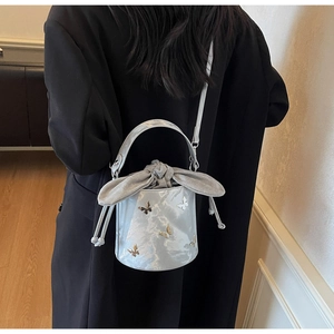 Detail of silver bucket bag with 3D butterflies and grey velvet bow on model