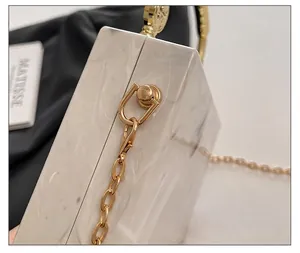 Close-up of premium gold hardware and marble-patterned acrylic on the evening handbag