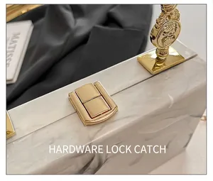 Close-up of golden hardware clasp and marble texture on stylish acrylic evening clutch