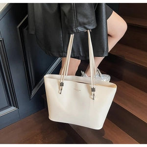 Macro detail of creamy white tote bag featuring lychee texture and gold logo lettering