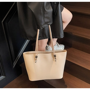Close-up of the beige tote bag showing refined texture and gold stamped logo detail