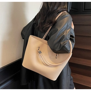 Close-up of a beige leather tote bag with litchi texture and metallic hardware details
