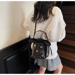Detail of black bucket bag with silver butterfly appliques and large satin bow decoration