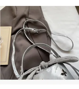 Detail of silver bucket bag showing grey suede bow and smooth adjustable long strap