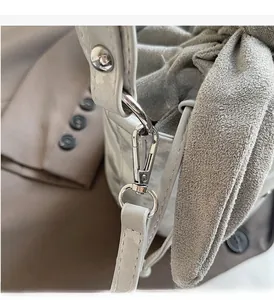 Detail of premium silver metal clasp and ring on a textured light grey soft bucket bag