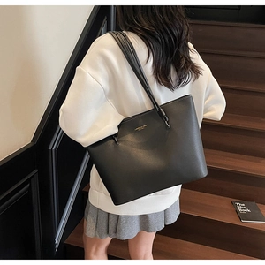 Detail of black leather tote bag with gold logo lettering and white contrast stitching