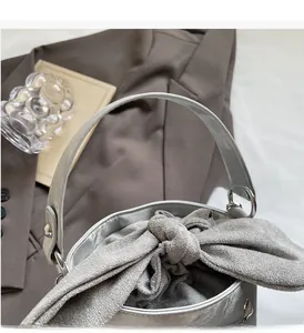 Close-up of the silver bucket bag showing the unique grey fabric knot and metallic handle