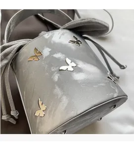 Detail of silver bucket bag with 3D metal butterfly studs and metallic marble texture