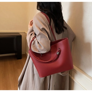 Detailed view of large red leather tote bag with fine texture and slim shoulder straps