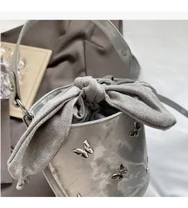 Detail of silver bucket bag with 3D metal butterflies and a grey drawstring bow closure