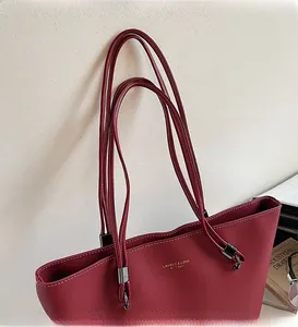 Detail view of burgundy leather tote bag featuring stitching and gold logo lettering