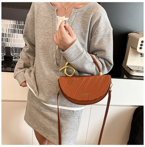 Detail of brown half-moon bag with 3D wave texture and golden spiral handle