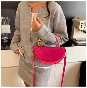 Detail of fuchsia semi-circle leather handbag with a gold knot handle and textured finish