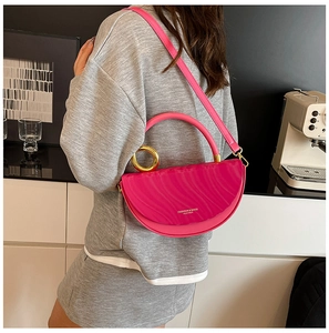 Detailed side view of a magenta half-moon bag with wave texture and gold hardware