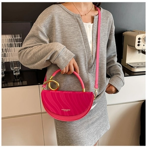 Close-up of rose red textured leather handbag with gold ring handle and wavy pattern