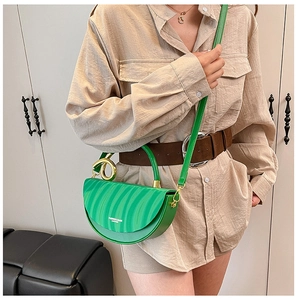 Detail of green leather saddle bag with wave pattern and golden ring handle